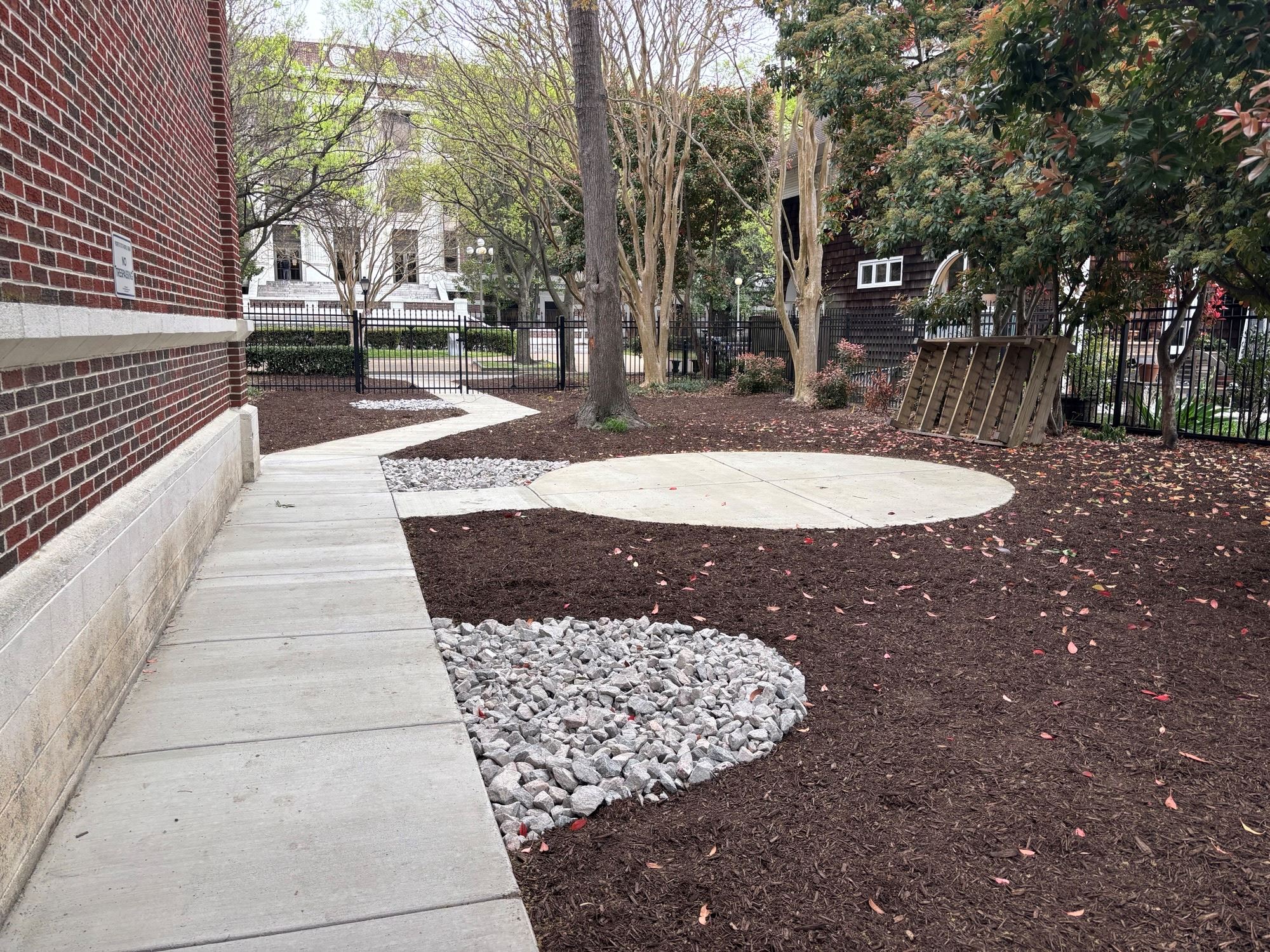 Photo of sidewalk leading out of a fenced in backyard.